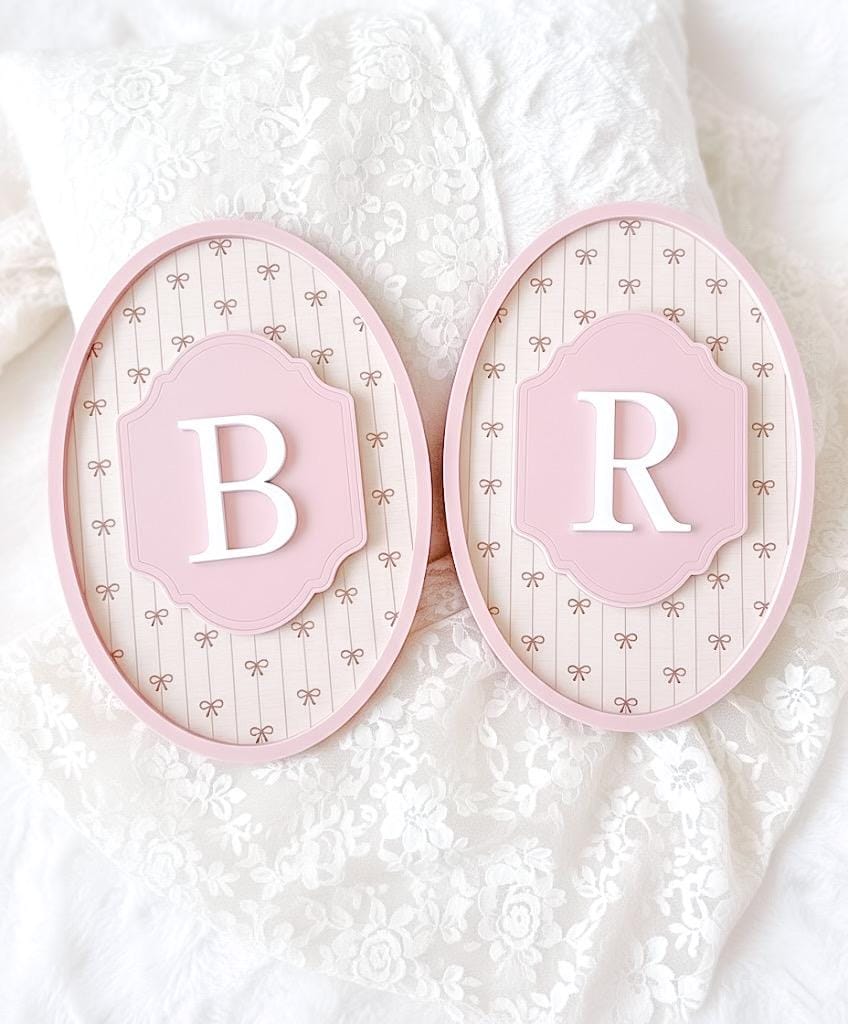 Two pink decorative plates with letters 'B' and 'R' on a textured white background